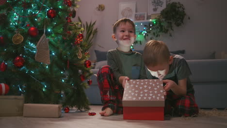 Zwei-Jungen-öffnen-Gemeinsam-Ein-Weihnachtsgeschenk-Unter-Dem-Baum.-Licht-Aus-Einem-Geschenk.-Hochwertiges-4K-Filmmaterial